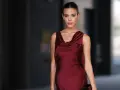 Una mujer elegante con un vestido burdeos satinado, ideal para saber como combinar un vestido burdeos para una boda.