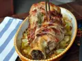 Stinco di vitello al forno, avvolto in pancetta e cotto con cipolle e rosmarino, pronto per essere servito.