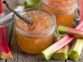 Confiture de rhubarbe maison, avec une gousse de vanille, sur un fond de tiges de rhubarbe fraîches.