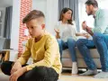 Trauriger Junge sitzt allein, während Eltern streiten. Die Vorteile eines Nebenwohnsitzes für Kinder sind oft, dass sie in einer ruhigeren Umgebung aufwachsen können.