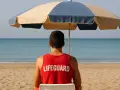 Giovane bagnino sorveglia la spiaggia, un'idea per lavori estivi per minorenni.