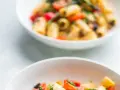 Due ciotole bianche piene di pasta con verdure colorate, un piatto estivo invitante.