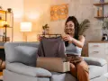 Mujer sonriente desempaqueta una camiseta gris. Espera que las medidas cuerpo sean perfectas.