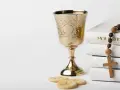 Złoty kielich, hostie, różaniec i Biblia. Symbolika sakramentu, który może być odnotowany w akcie chrztu.