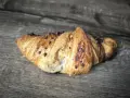 Chrupiący croissant z kawałkami czekolady na drewnianym tle. Idealny na śniadanie, choć warto sprawdzić jego kcal.