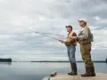 Dwóch starszych panów na pomoście, łowiących ryby. Ich wyprawy na ryby w Polsce to tradycja.