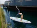 Frau macht Yoga-Brücke auf SUP-Board. Stand up paddle gesund und fördert Balance.