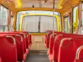 Wnętrze żółtego autobusu z czerwonymi siedzeniami, widok od tyłu.