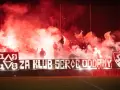 Fani z piłą ręczną, czuwaj przemyśl! Tłum kibiców z racami i flagami tworzy czerwony dym.