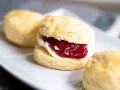 Frisch gebackene Scones mit Clotted Cream und Erdbeermarmelade, ein köstliches Rezept für den Nachmittagstee.