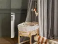 Przytulny kącik dla dziecka w pokoju rodziców: wiklinowy kosz z pluszakami, białe łóżeczko i delikatne zasłony tworzą spokojną atmosferę.