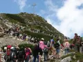 Tłum turystów wspina się na Giewont, podziwiając widok z Kasprowego Wierchu. Na szczycie widoczny krzyż.