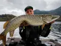 Glücklicher Angler hält stolz einen großen Hecht im Boot. Ein erfolgreicher Tag auf Hecht angeln!