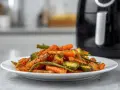 Un piatto di verdure miste, come carote, zucchine e fagiolini, cotte alla perfezione nella friggitrice ad aria, con un contorno dorato e saporito.