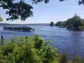 Ein Ausflugsboot fährt auf einem glitzernden See bei Potsdam. Grüne Bäume säumen das Ufer, ideal für einen entspannten Tag an den Badeseen Potsdam.