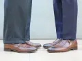 Długość spodni garniturowych: jeden model ma wywinięte nogawki, drugi gładkie. Eleganckie buty męskie.