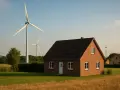 Domy w otoczeniu pól i wiatraków, symbolizujące nowe możliwości dzięki ustawie wiatrakowej.
