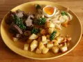 En tallrik med stekt kött, stekt potatis, stekt lök och ett kokt ägg. En klassisk rätt som representerar svenskt mat.