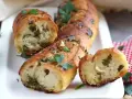 Pan de ajo recién horneado, dorado y crujiente, con trozos de perejil y ajo visibles en su interior.