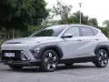 Szary Hyundai Kona Hybrid stoi na zewnątrz, z widocznym przodem i bokiem.