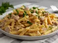 Penne z kurczakiem w kremowym sosie, posypane natką pietruszki. Pyszne danie, które zadowoli każdego miłośnika makaronu.