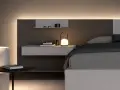 Elegante boiserie camera da letto moderna con illuminazione integrata, comodino sospeso e lampada di design.