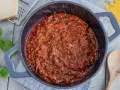 Herzhafte, beste Bolognese original im Topf, mit frischem Basilikum, Parmesan und Spaghetti daneben.