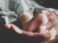 Delikatne stópki dziecka w dłoni, otulone miękkim kocykiem. Idealne dla nich jest pranie w proszku do prania dla dzieci.