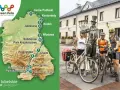 Rodzina na rowerach przy pomniku, planując podróż po szlaku Green Velo.