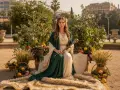 Mujer con túnica verde y blanca, rodeada de frutas y espigas, evoca la templanza y la emperatriz tarot.