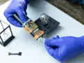 Gloves prepare to apply Gorilla Epoxy, known for its incredible strength, to a small glass and metal object.