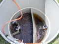 Wnętrze zbiornika biofos z ciemną wodą i rurami.