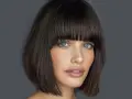 Elegancka kobieta po czterdziestce z modną fryzurą z grzywką. Jej niebieskie oczy przyciągają wzrok.