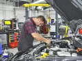 Mecánico trabajando en un motor en un taller. El sistema ERP del taller está organizado y listo para el diagnóstico.