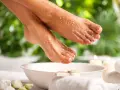 Pieds doux et soignés, recouverts de sel pour un gommage naturel. Une invitation à découvrir comment enlever la peau morte des pieds.