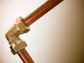 Un coude en laiton relie deux tuyaux en cuivre. Ce raccord per cuivre est essentiel pour les installations de plomberie.