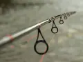 Idealny spinning na szczupaka z brzegu, z pomarańczową żyłką przechodzącą przez przelotki.