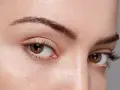 Gros plan sur des yeux aux cils longs et recourbés, encadrés par des sourcils aux forme sourcils parfaits.