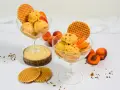 Zwei Gläser mit cremigem Aprikosen Eis, garniert mit frischen Aprikosenstücken und Waffeln. Ein sommerlicher Genuss!