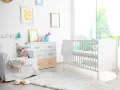 Stanza luminosa con lettino bianco, poltrona comoda e decorazioni a tema neonato. Un nido accogliente per un piccolo tesoro.
