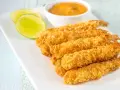 Crujientes gambas a la gabardina doradas, servidas con rodajas de lima y una salsa cremosa.