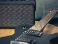 Czarna gitara elektryczna i mały wzmacniacz – to podstawa, co jest potrzebne do gitary elektrycznej, by zacząć grać.
