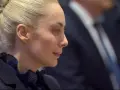 Marta Fascina, con i capelli raccolti, indossa un abito scuro. La sua espressione pensierosa suggerisce un momento di riflessione prima di un evento importante, forse legato a Silvio Berlusconi.