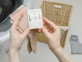 Sprawdź metkę: w ilu stopniach prac skarpety? Jasnoróżowe skarpety Steven z metką, obok koszyk i szare skarpety.