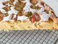Kawałek ciasta z rabarbarem, posypany cukrem pudrem. Wygląda na to, że zakalec się nie zrobił, a ciasto jest idealne.