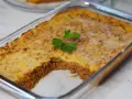Pastel de papa recién horneado en refractario de vidrio, con una porción retirada, decorado con perejil fresco.