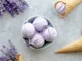 Schalen und Waffelkegel mit cremigem Lavendeleis, garniert mit frischen Lavendelzweigen.