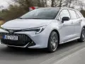 Srebrna Toyota Corolla 2.0 Hybrid w wersji kombi pędzi po drodze.