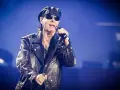 Klaus Meine, jung und rockig, singt ins Mikrofon, trägt Lederjacke und Kappe.