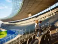 Zwei Kinder stehen auf den Rängen des Olympiastadion Berlin und blicken auf die Laufbahn.